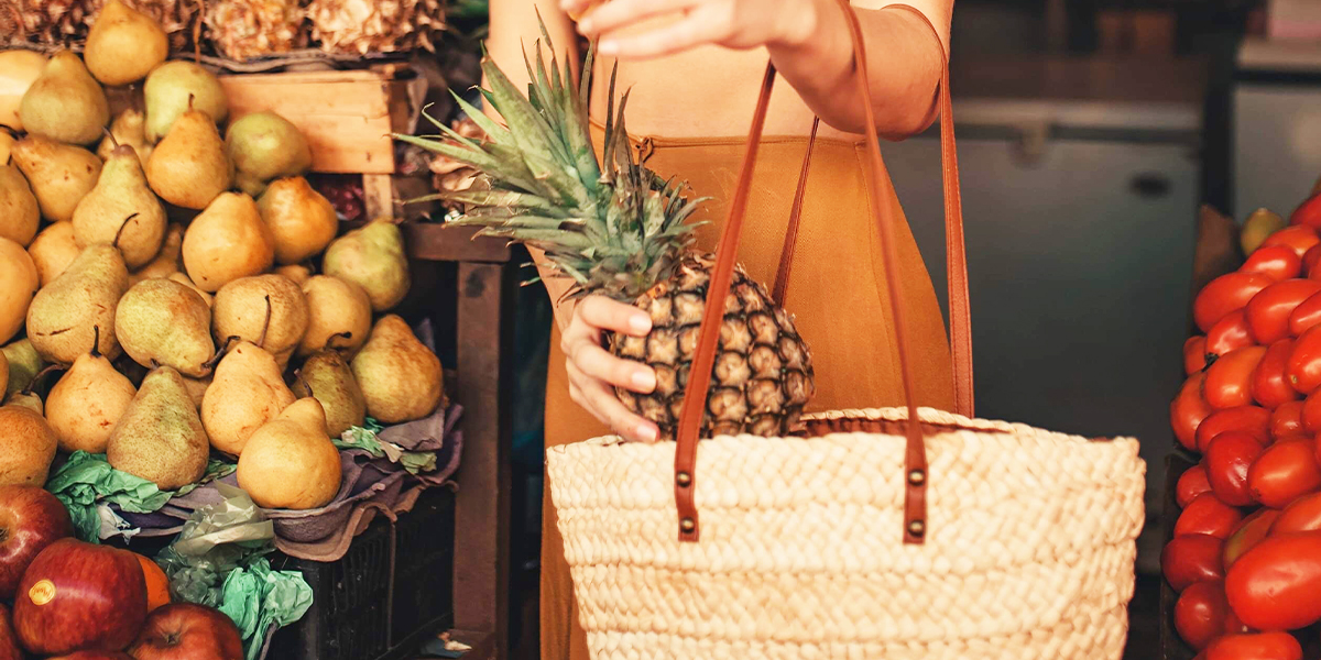 woman putting pineapple in shopping bag