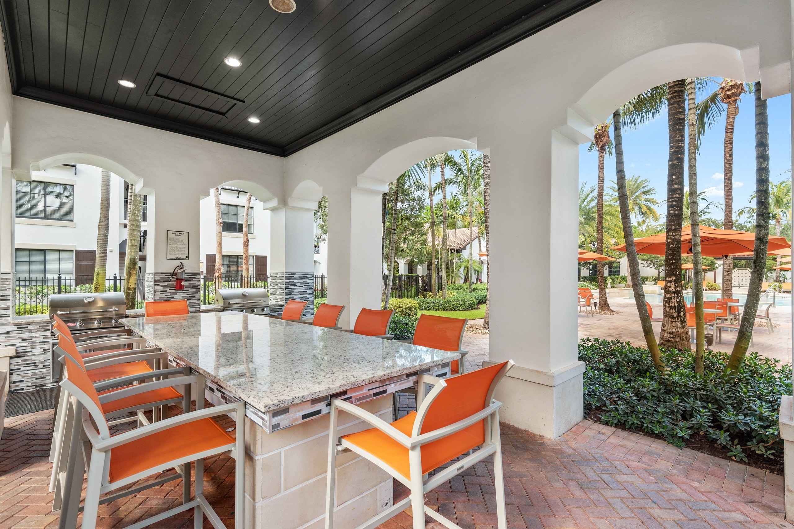 Daytime view of AMLI Toscana Place built in barbeque seating area with free standing island and high top seating
