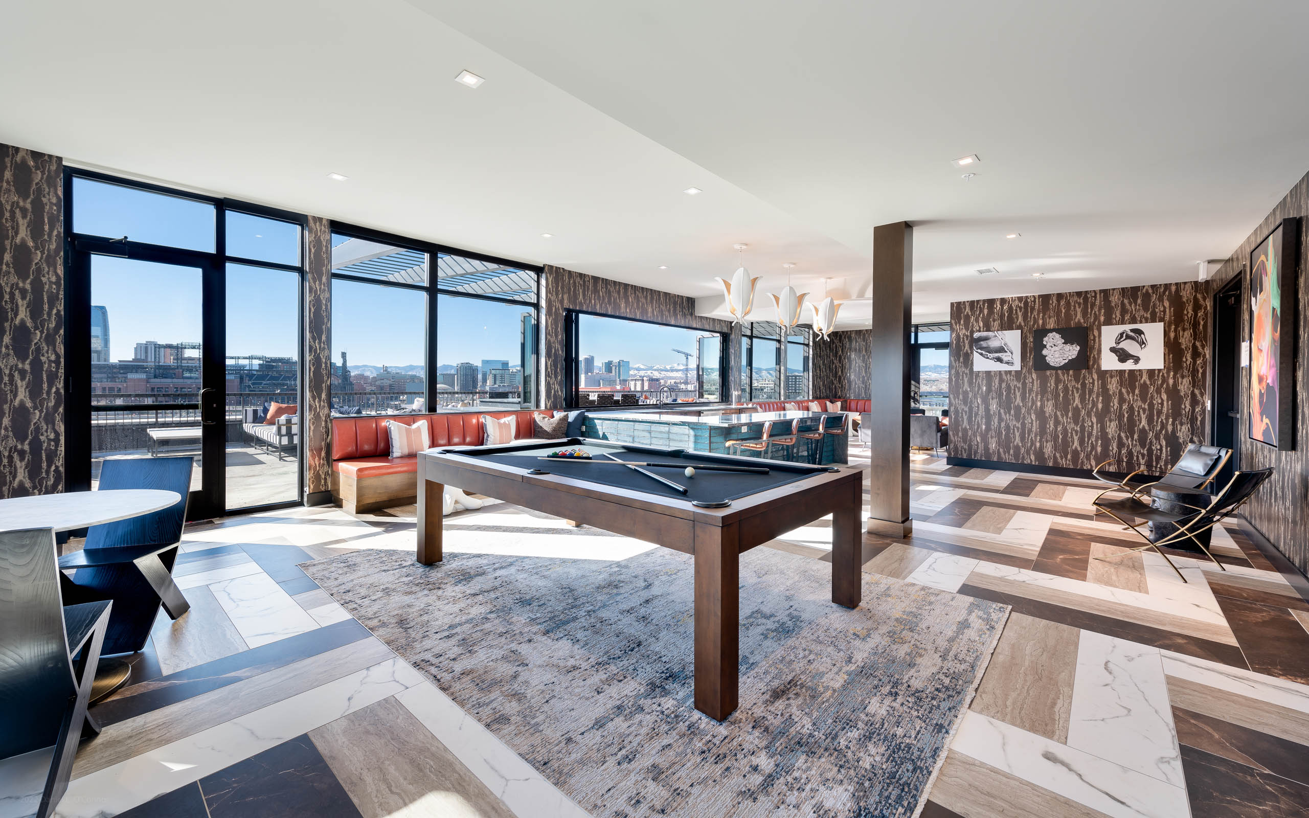 Interior view of a resident sky lounge at AMLI Art District with a pool table and bar area and a view of downtown Denver 