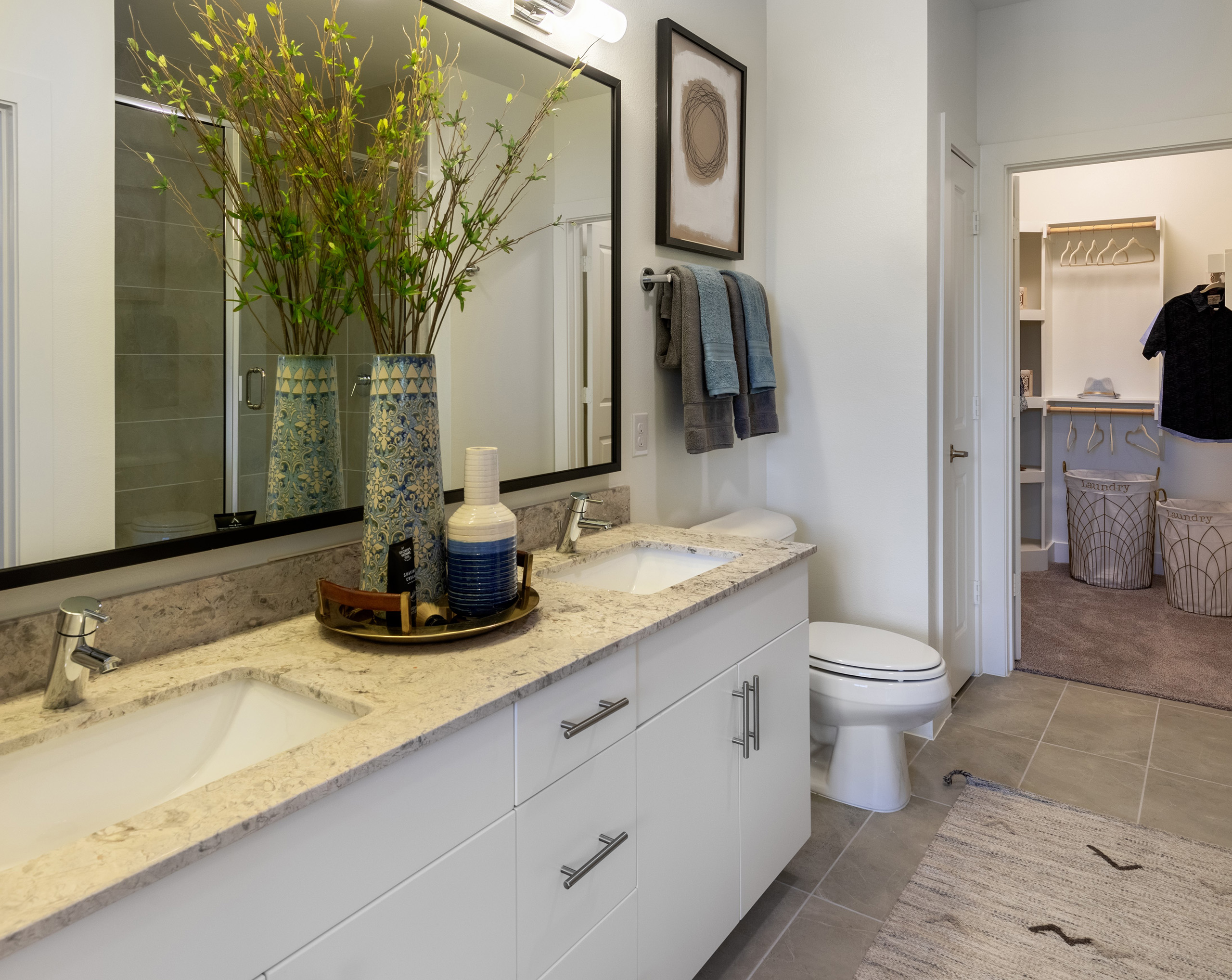 Interior view of AMLI Grapevine apartment bathroom with white granite countertops and a double vanity and a walk-in closet