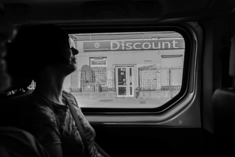 Woman in a van passing a storefront with a disount sign