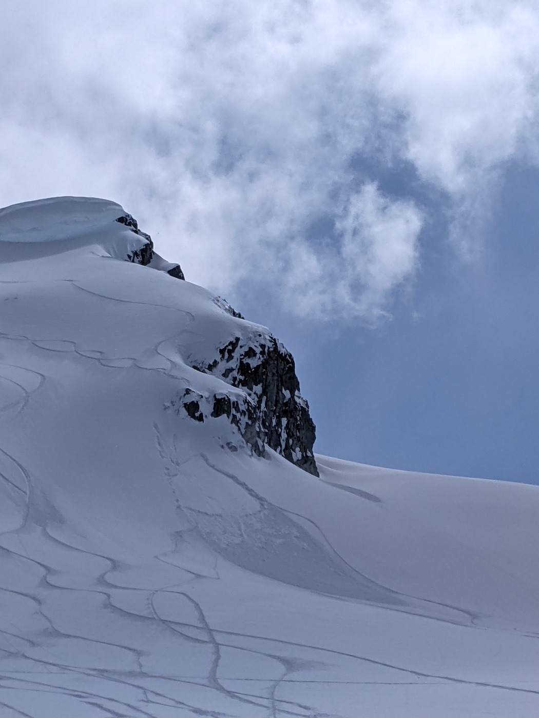 Numerous tracks on the bottom left of the image. In the centre is a small avalanche triggered below a cliff.