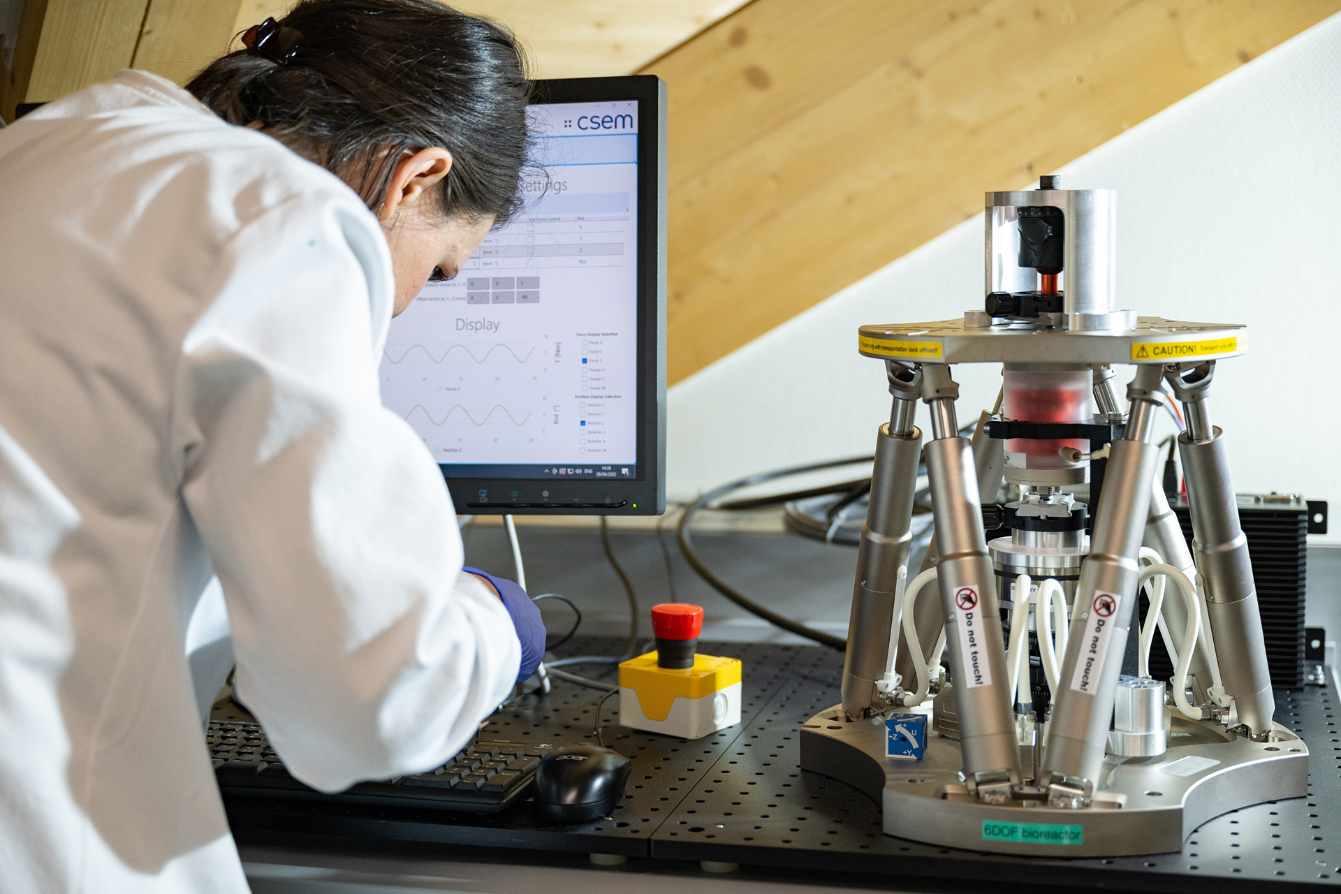 A lab technician operates the benchtop multiaxial bioreactor system.
