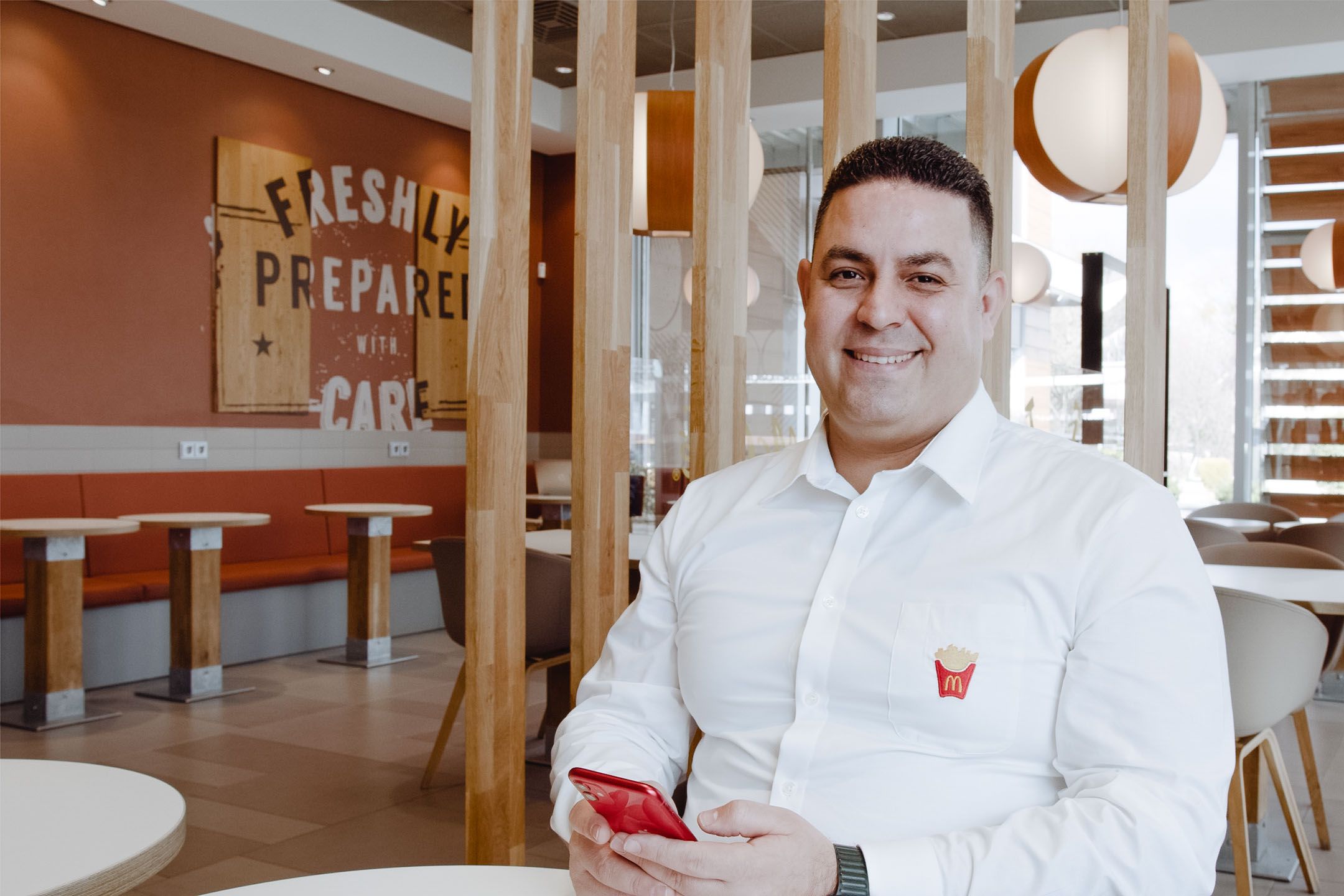 McDonald's employee smiling and using his smartphone