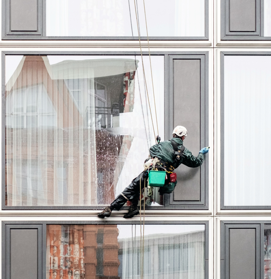 Berufsunfähigkeitsversicherung mit Risikoberuf - Fensterreiniger hängt an Seilen vor Fassade berufsunfaehigkeitsversicherung-risikoberuf