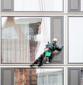 Berufsunfähigkeitsversicherung mit Risikoberuf - Fensterreiniger hängt an Seilen vor Fassade berufsunfaehigkeitsversicherung-risikoberuf