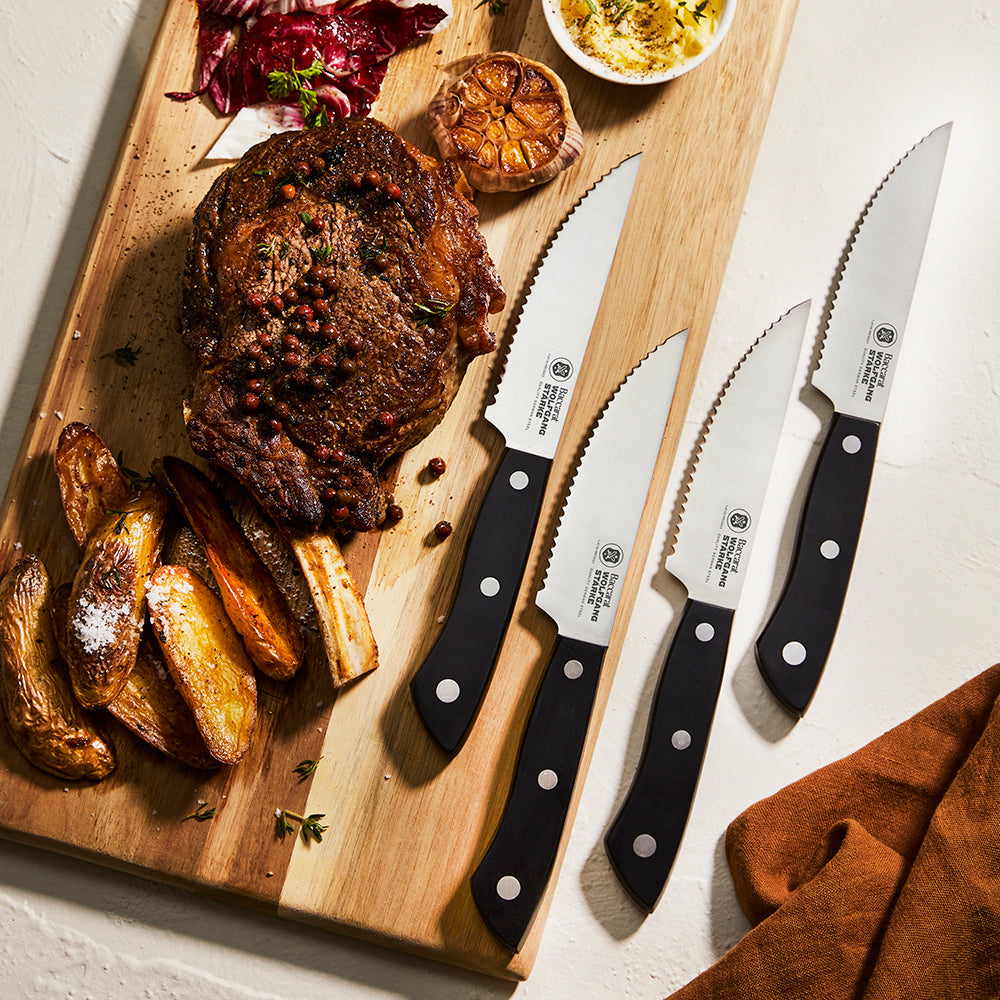 Father's day gift guide. Baccarat Set of 4 steak knives on a chopping with steak and chips.