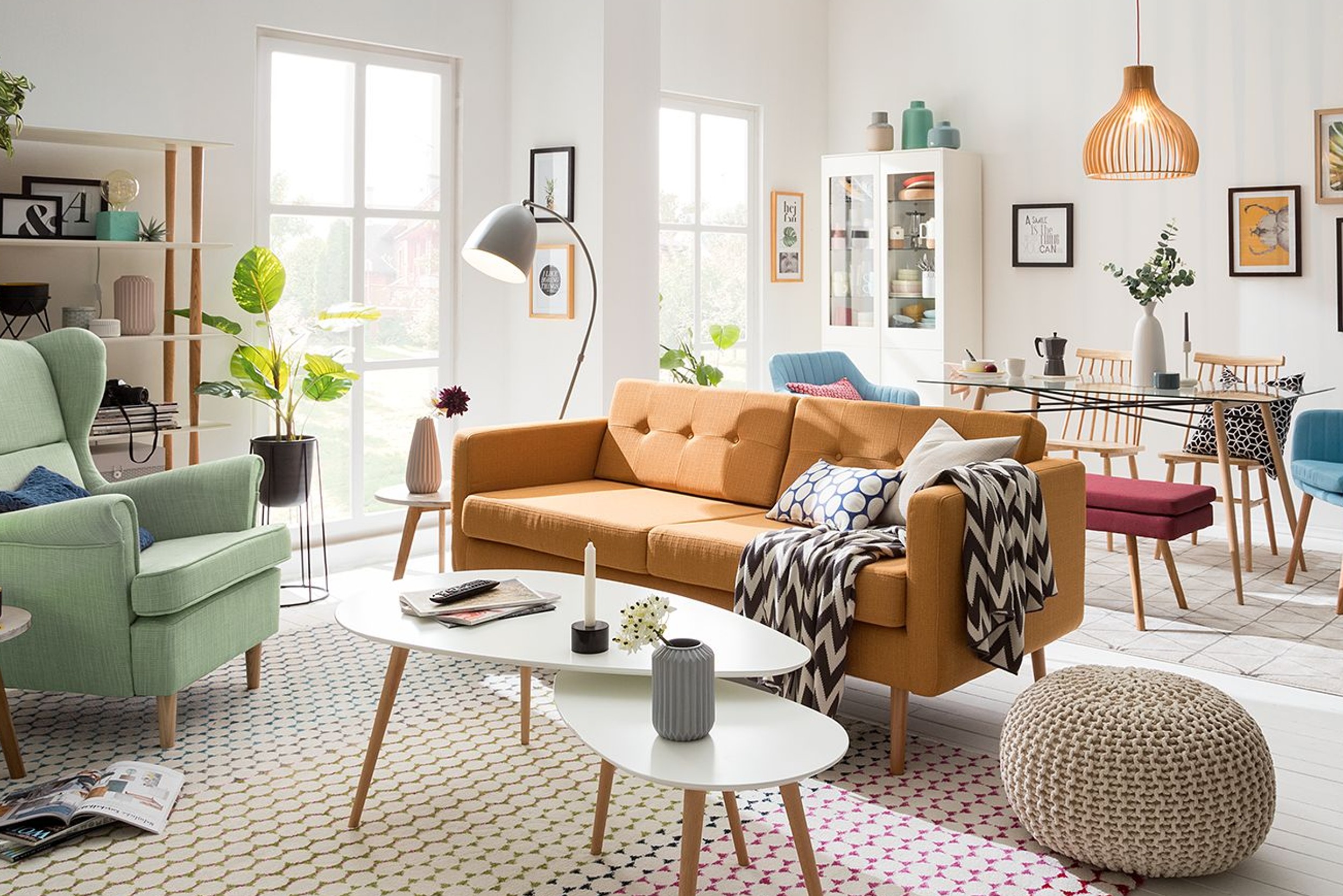 Orangenes Sofa separiert den Wohnbereich mit Sessel und Beistelltisch vom Essbereich mit Geschirrschrank und Esstisch