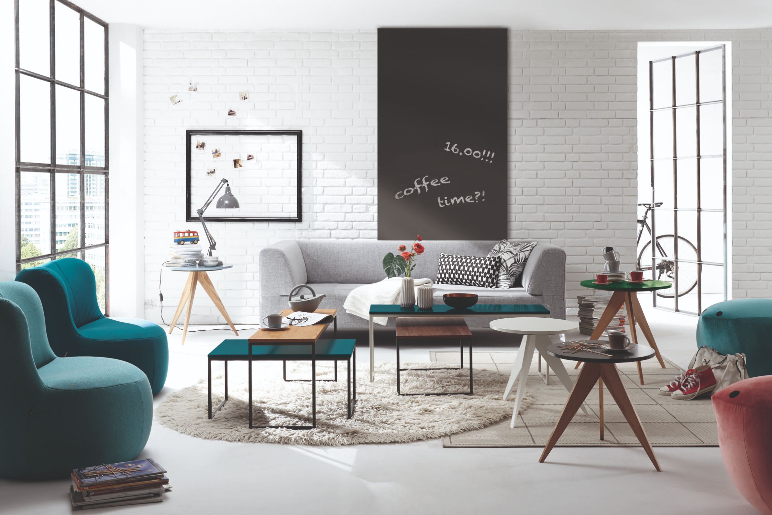 Wohnzimmer mit grauem Sofa und verschiedenen Couchtischen