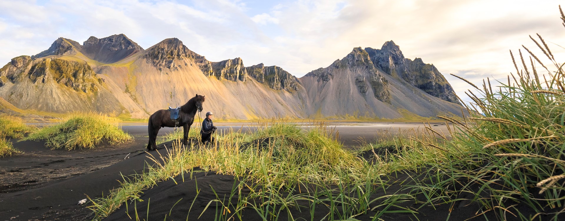 An Icelandic horse and its rider on a black beach in Iceland