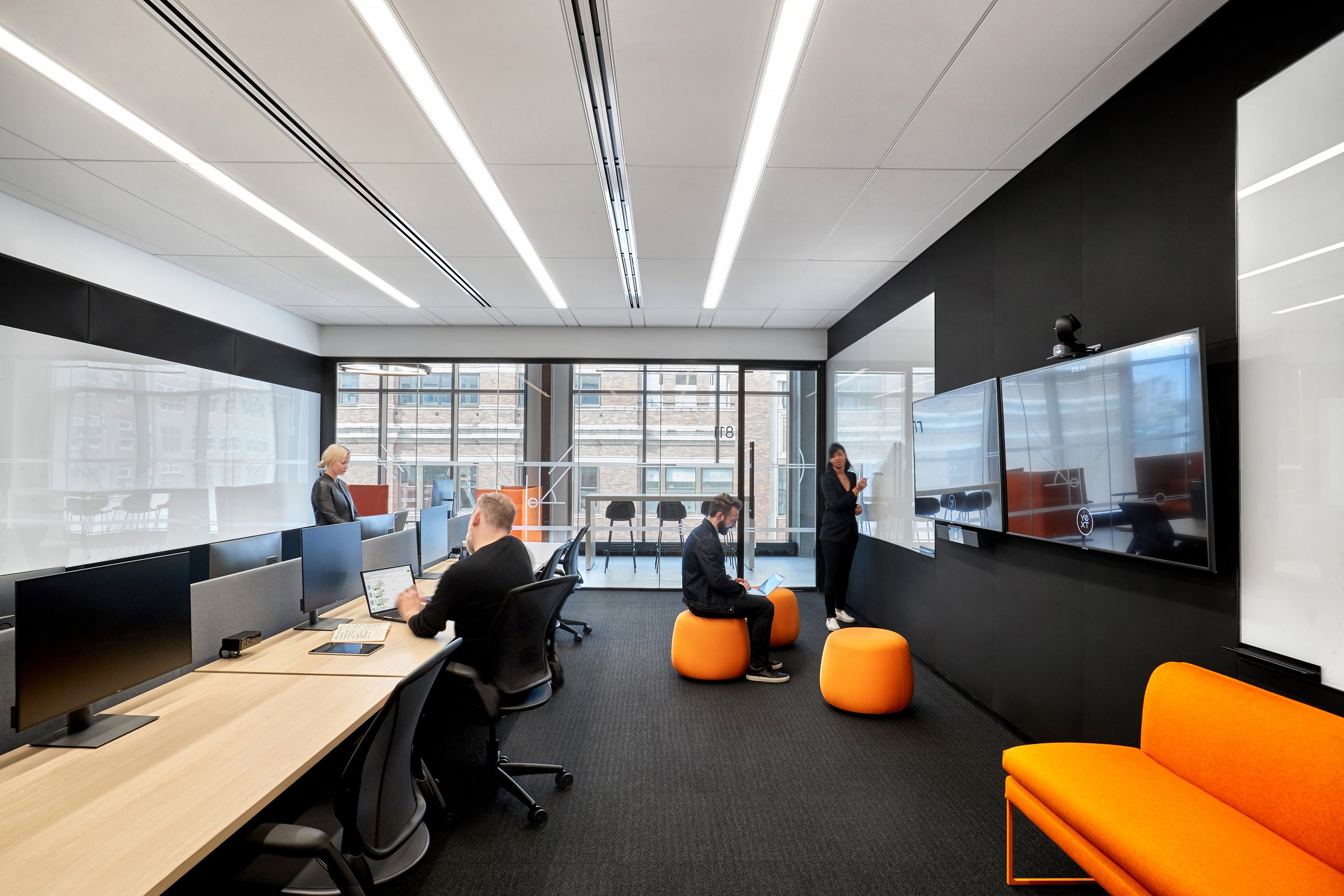 Corporate meeting room with digital screens and collaborative seating, showcasing UX design examples in workplace technology integration.