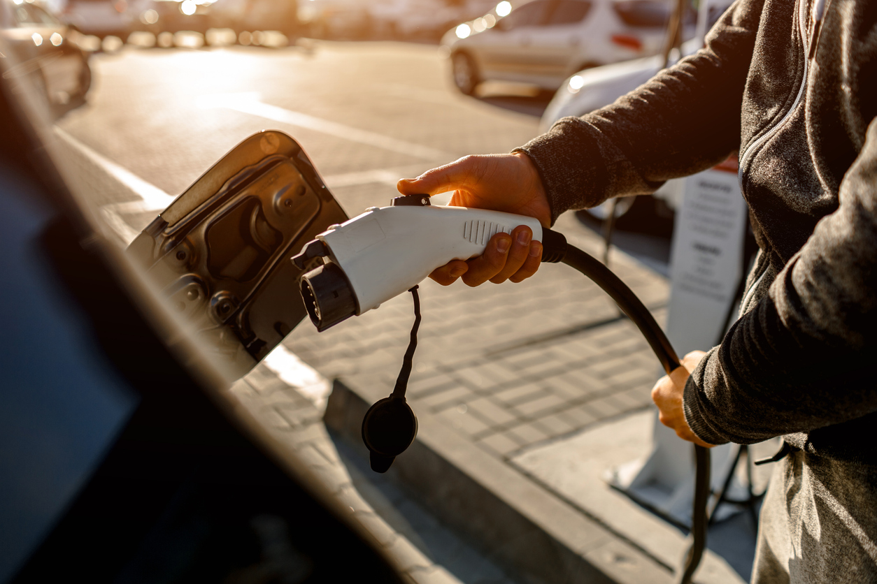 Homme se préparant à charger sa voiture électrique sur un parking extérieur