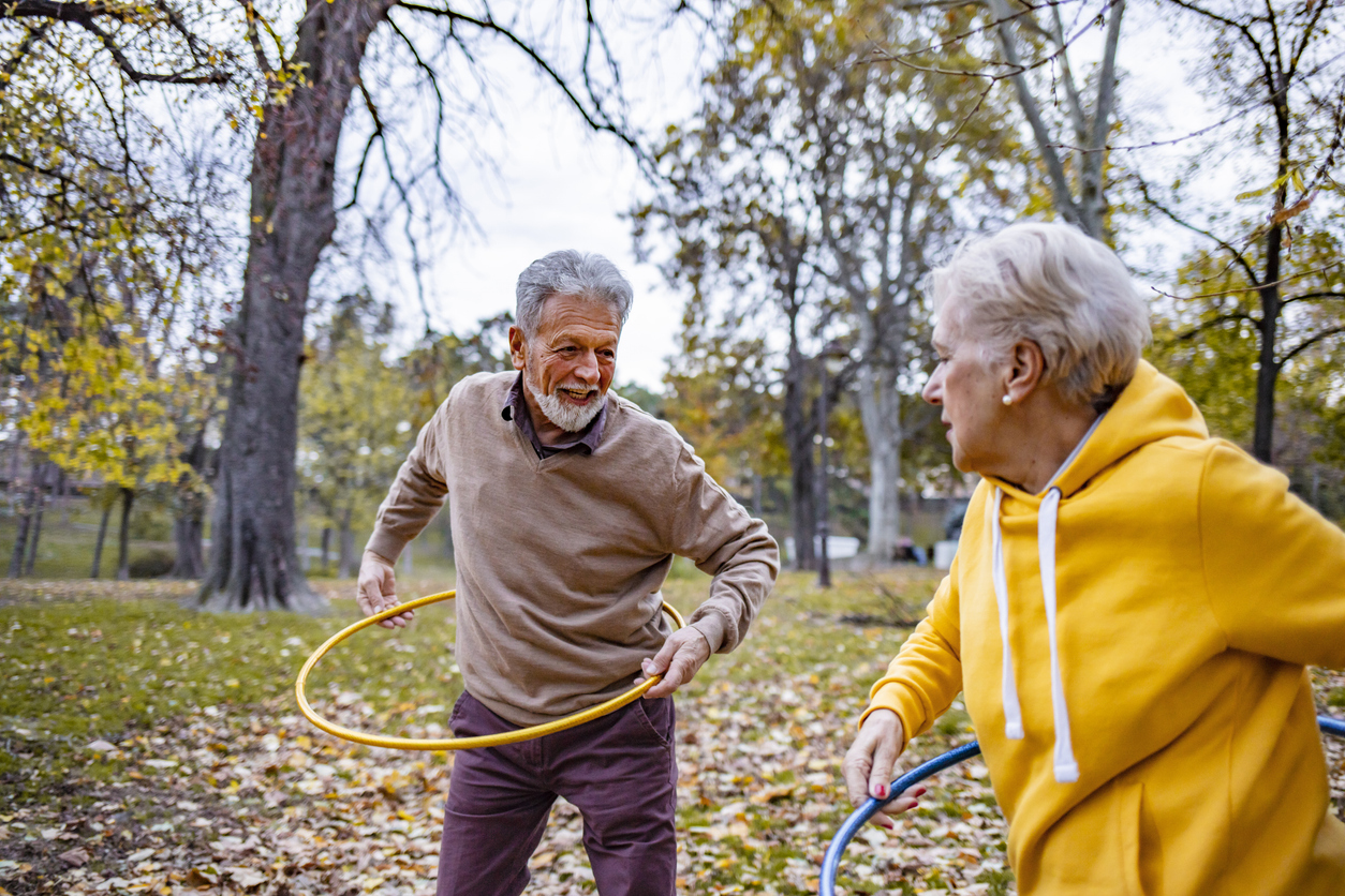 Deux seniors faisant du hula hoop dans un bois