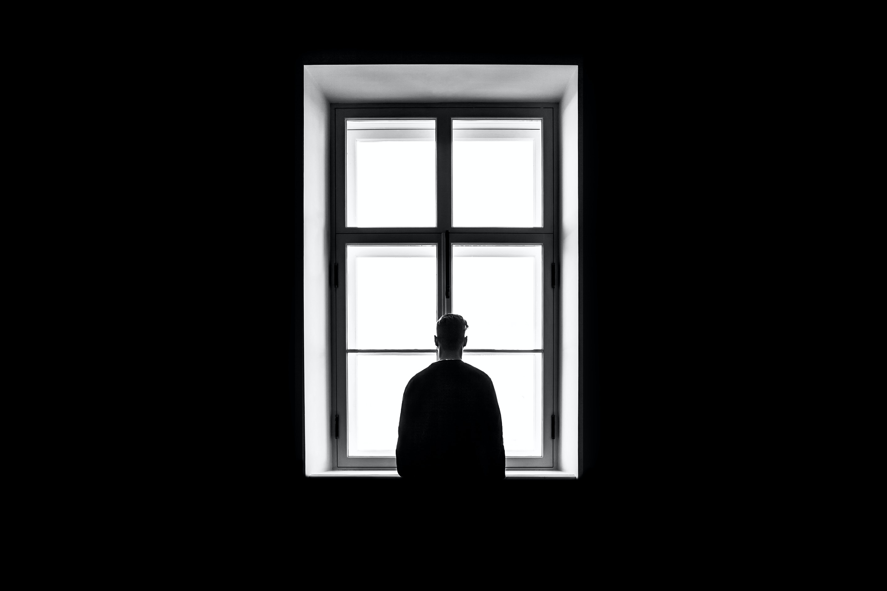 Person looking out of a window looking solemn