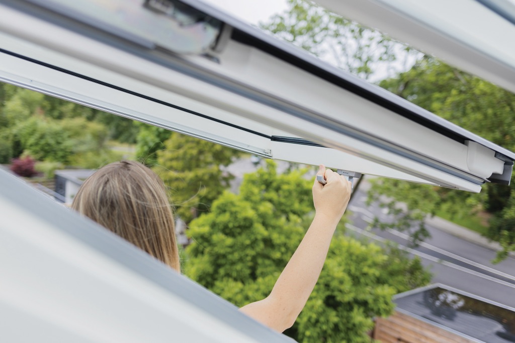 Frau öffnet ein Dachfenster – idealer Moment für den Dachfenster Austausch bei alten oder undichten Modellen