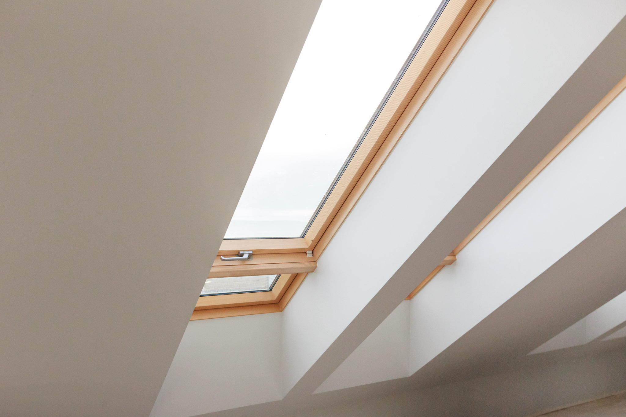 Innenansicht eines schrägen Dachfensters mit Holzrahmen – ideale Voraussetzung, um ein Dachfenster fachgerecht abzudichten und Energieverluste zu vermeiden. Innenansicht eines schrägen Dachfensters mit Holzrahmen – ideale Voraussetzung, um ein Dachfenster fachgerecht abzudichten und Energieverluste zu vermeiden.