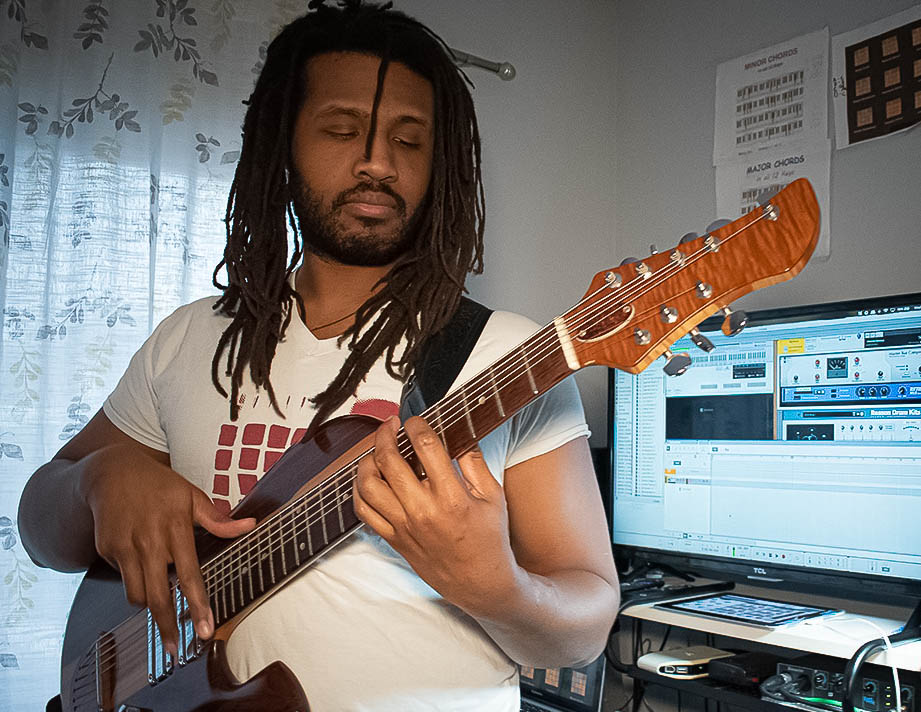 Godcloud playing the bass guitar in his home studio in Rochester.
