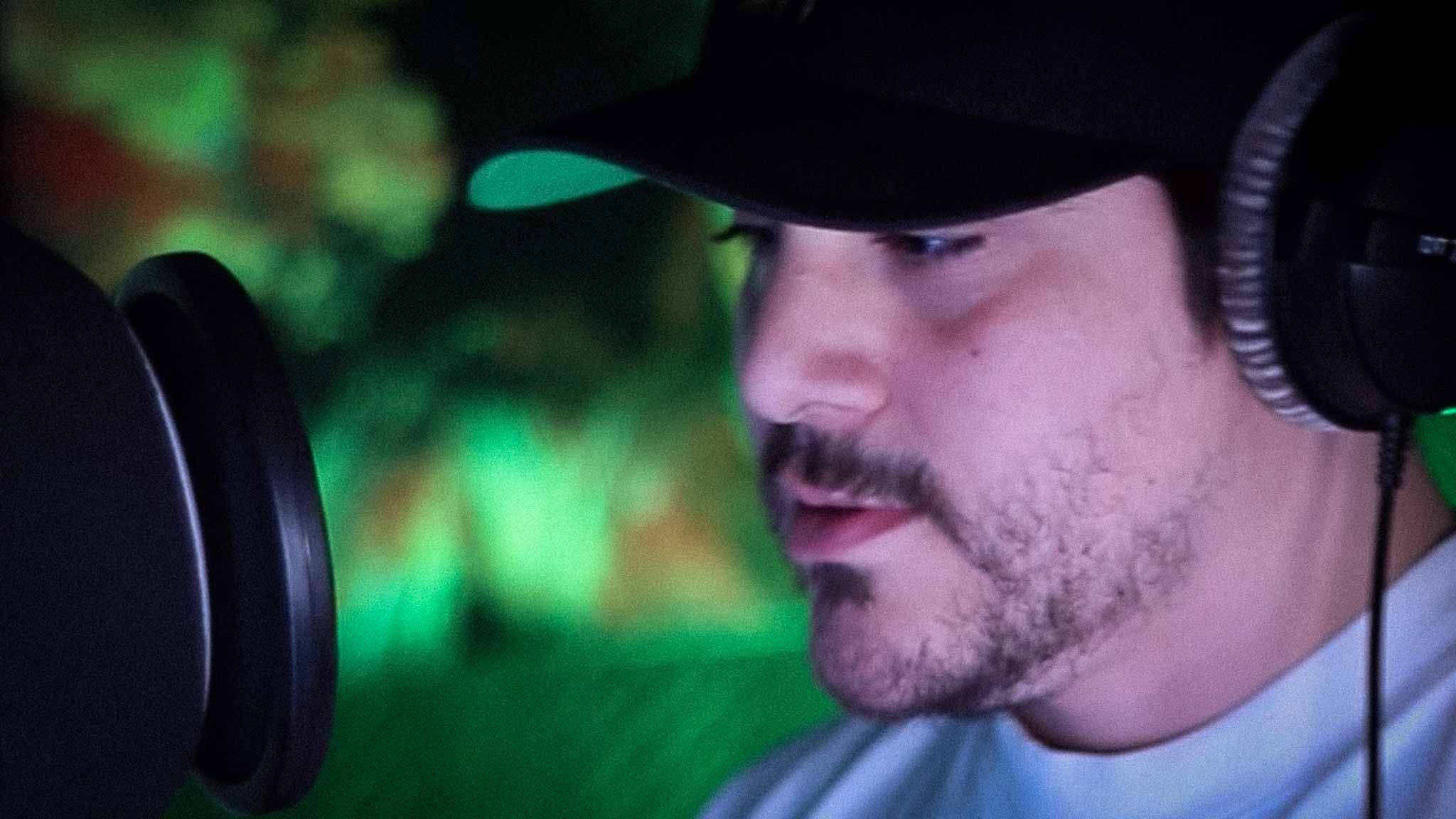 Louie C Rhymes standing at a microphone in a recording studio with Beyer headphones on.