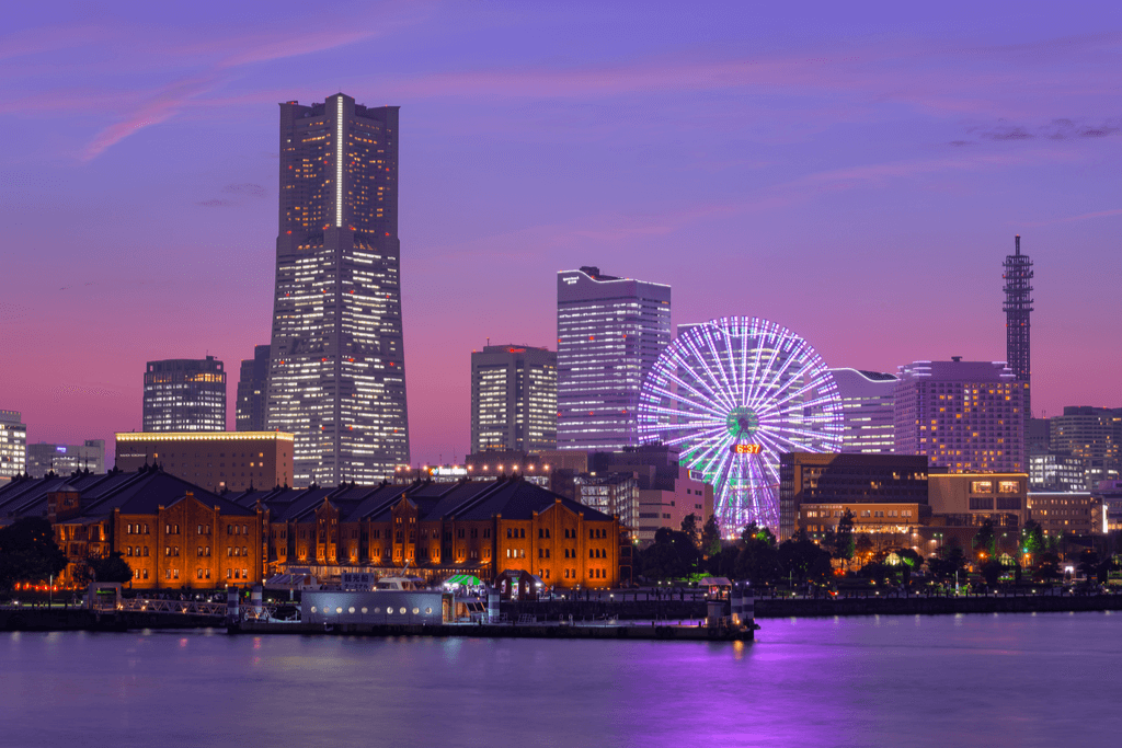 Many builidngs, a colorful ferris wheel, and the famous red brick warehouse with a sunset in the background.