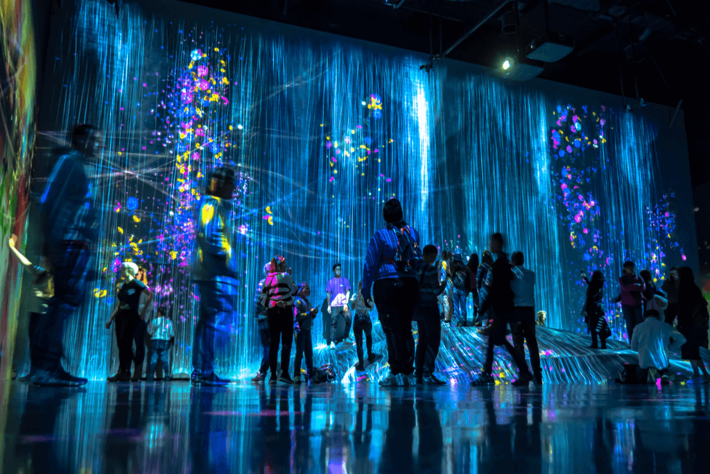 A group of people stand in front of an art display at Team Lab, a popular art installation and date spot.