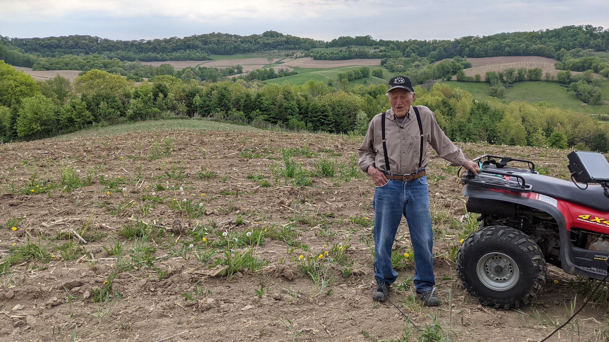 A farmer out in the field with his ATV four wheeler.
