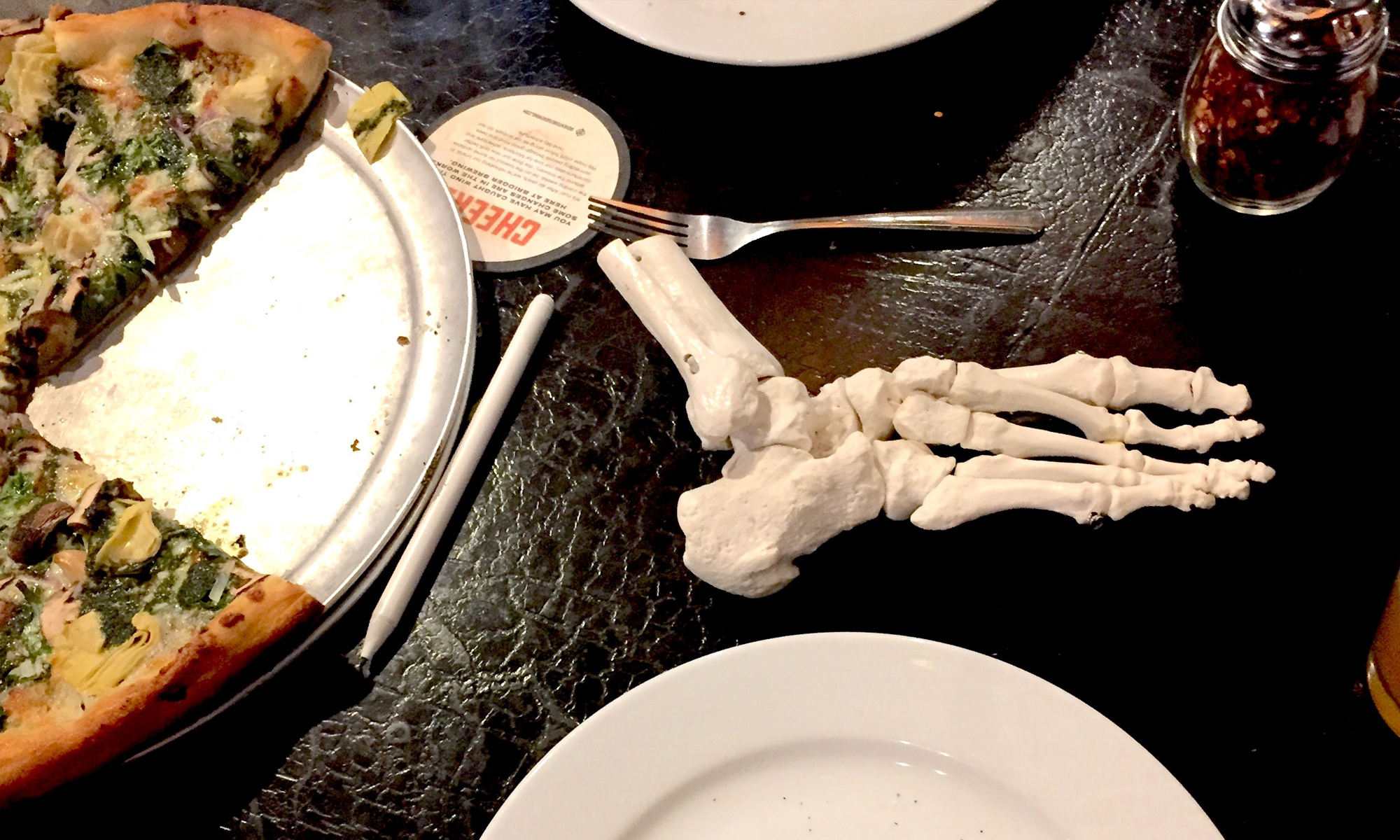 Human foot skeleton model and pizza staged for an informative Oboz article.