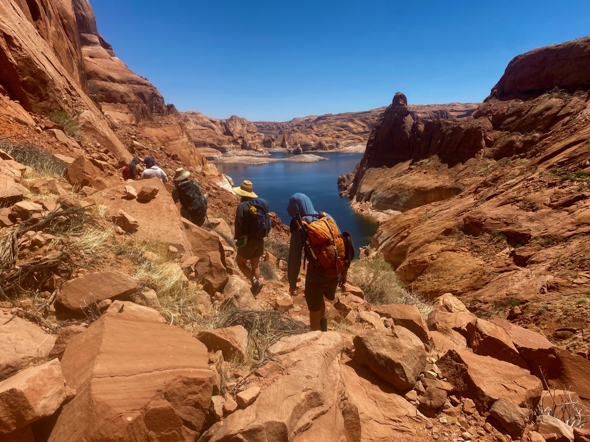 5 hikers walk towards a lake in David Canyon during the heat of the summer in their Oboz hiking boots