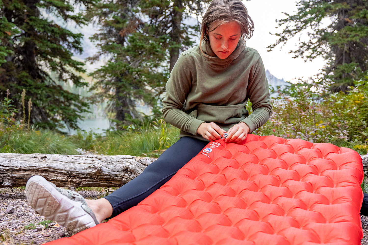 Hiker inflating a camping pad while wearing the Oboz Whakata Trail.