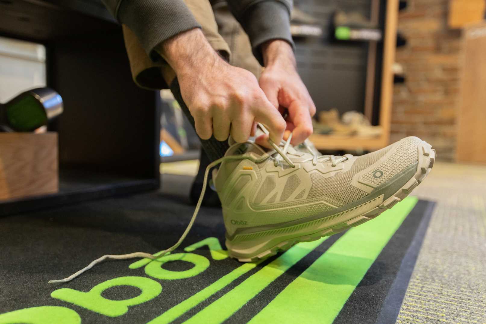 A person ties their Oboz Katabatic shoe during a fitting with an Oboz retailer. 