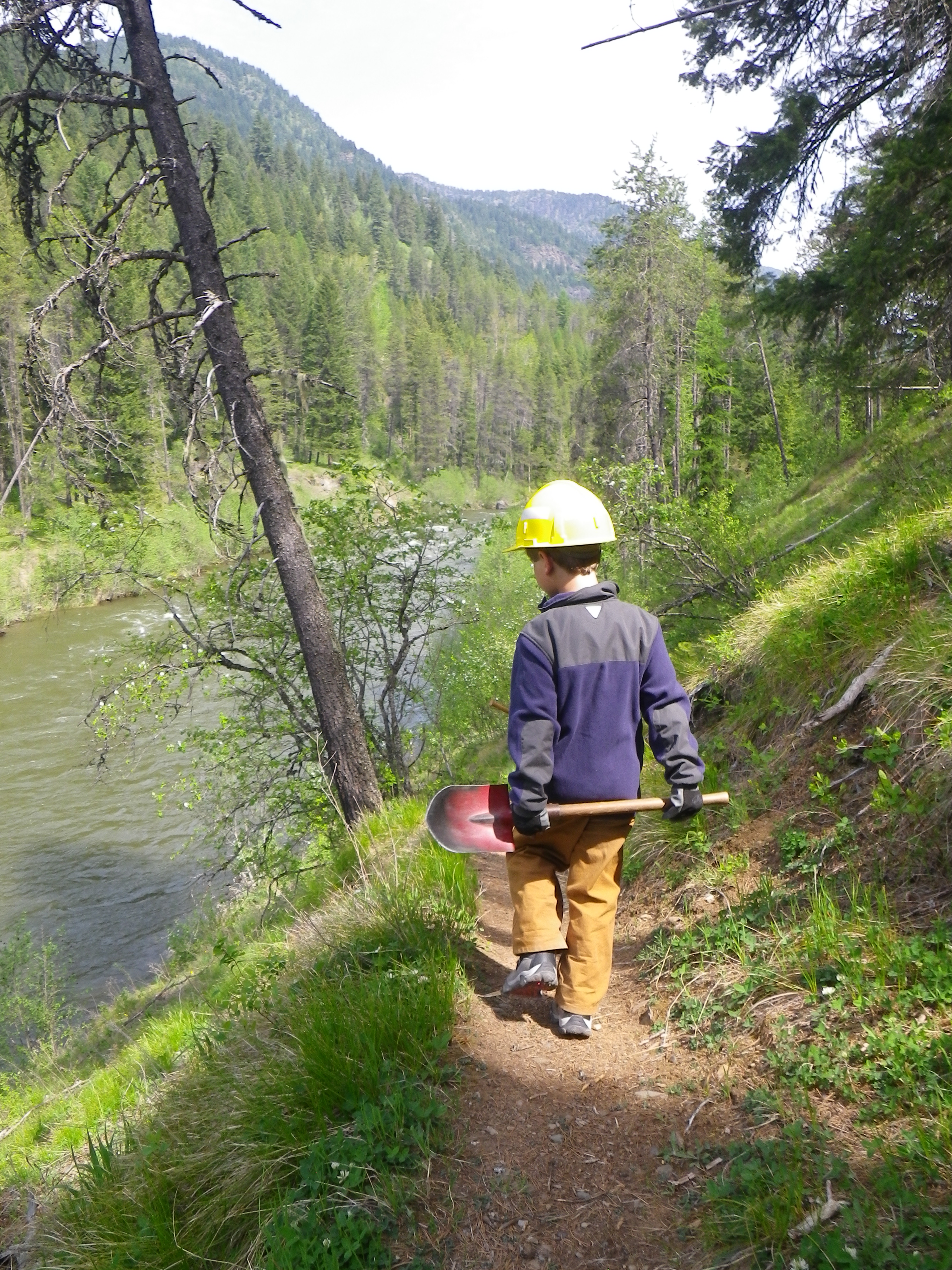 A young volunteer with a shovel working on a hiking trail in the Montana wilderness.