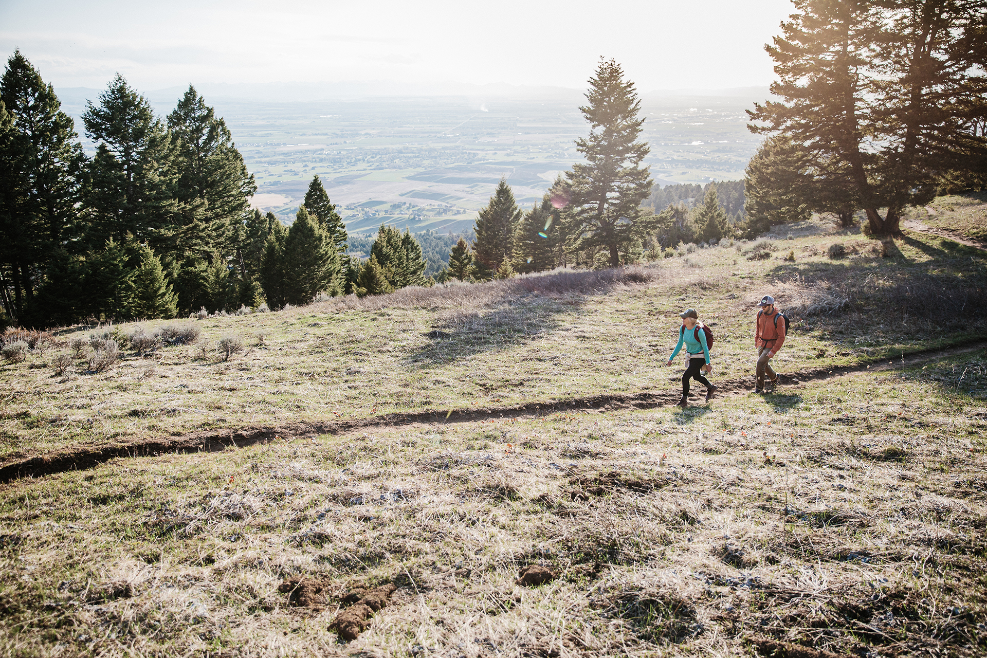 Two hikers trekking through the mountains on a trail in Montana.