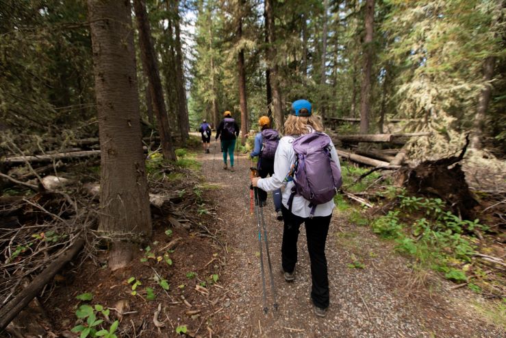 Women hike in Oboz hiking shoes through the Montana forest at the over 50 outside retreat with Oboz Footwear. 