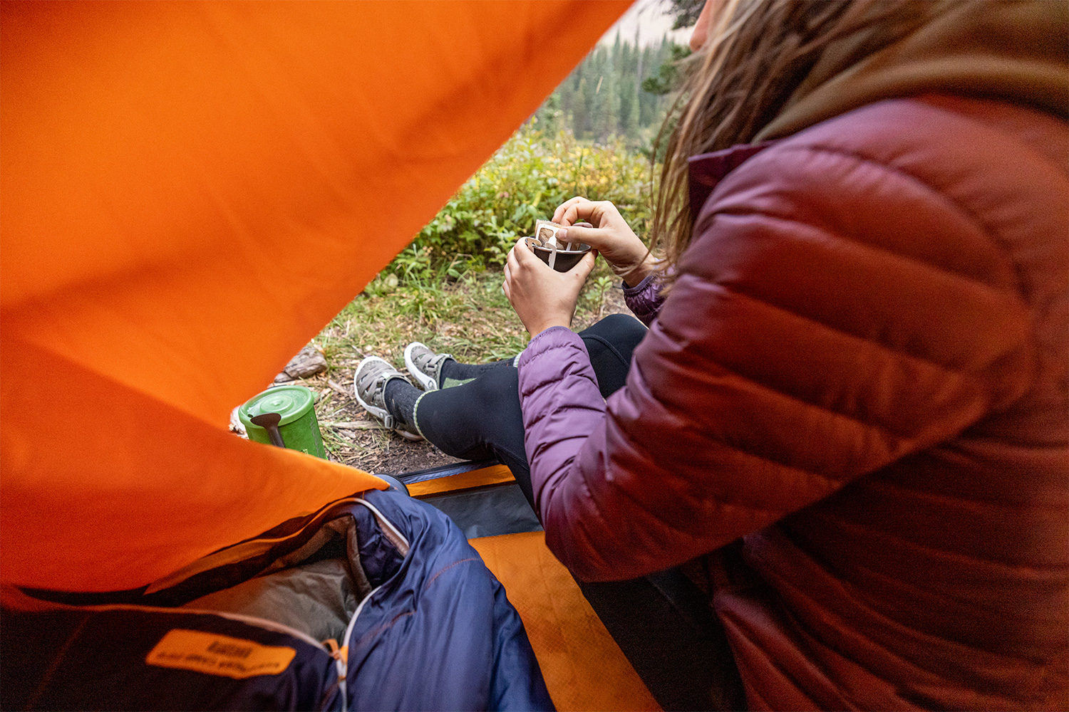 Hiker making coffee at camp while wearing the Oboz Whakata Trail sandal.