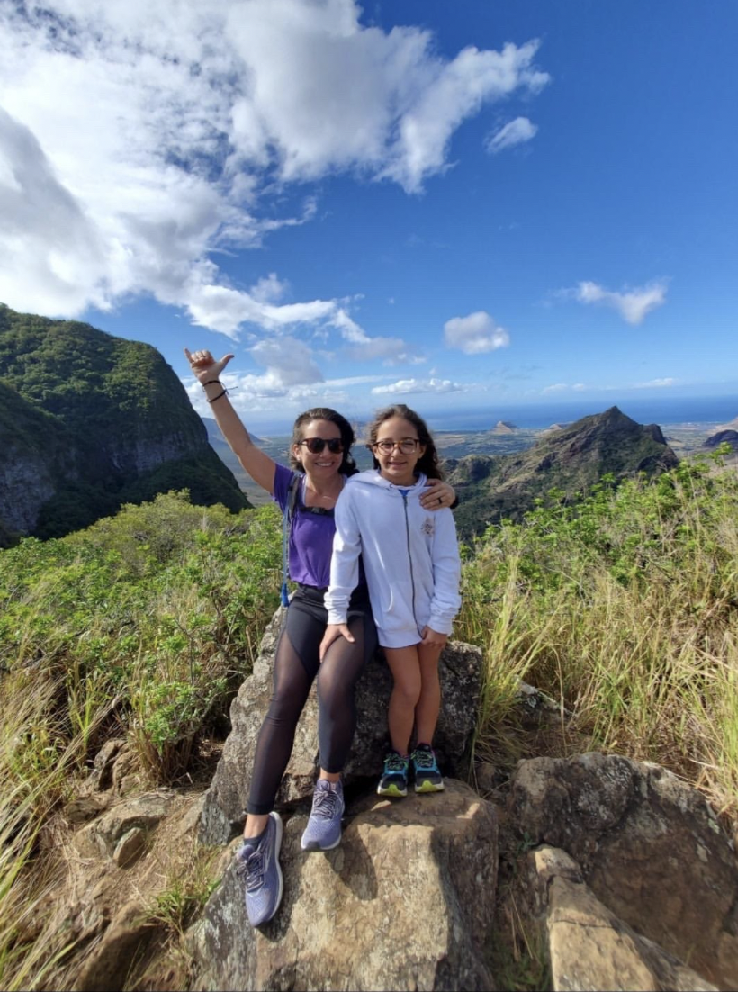 Woman and child smile while hiking on a trail during the summertime 