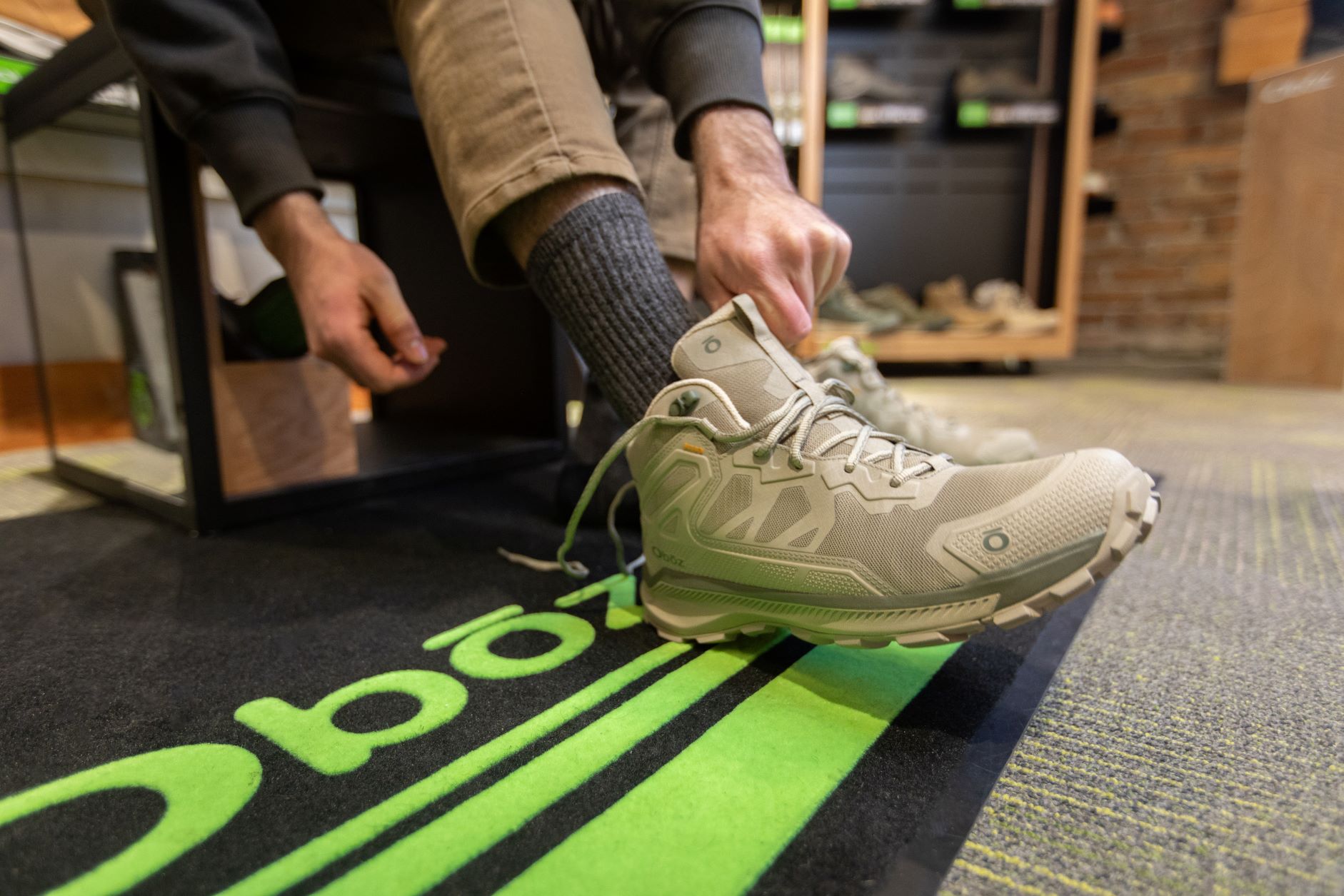 A person tries on an Oboz Katabatic Mid hiking shoe at a dealer. 
