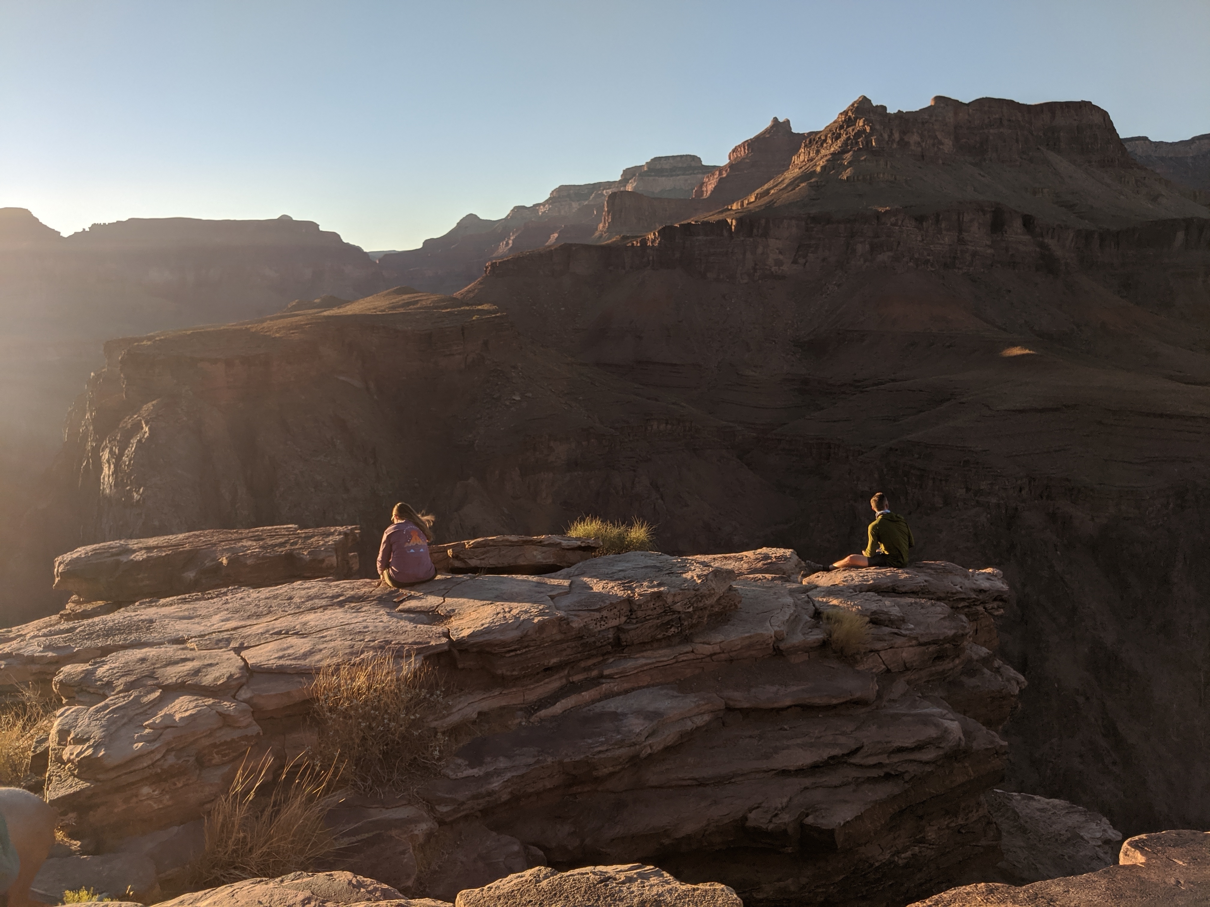 Two hikers overlooking a canyon on a bright, sunny day