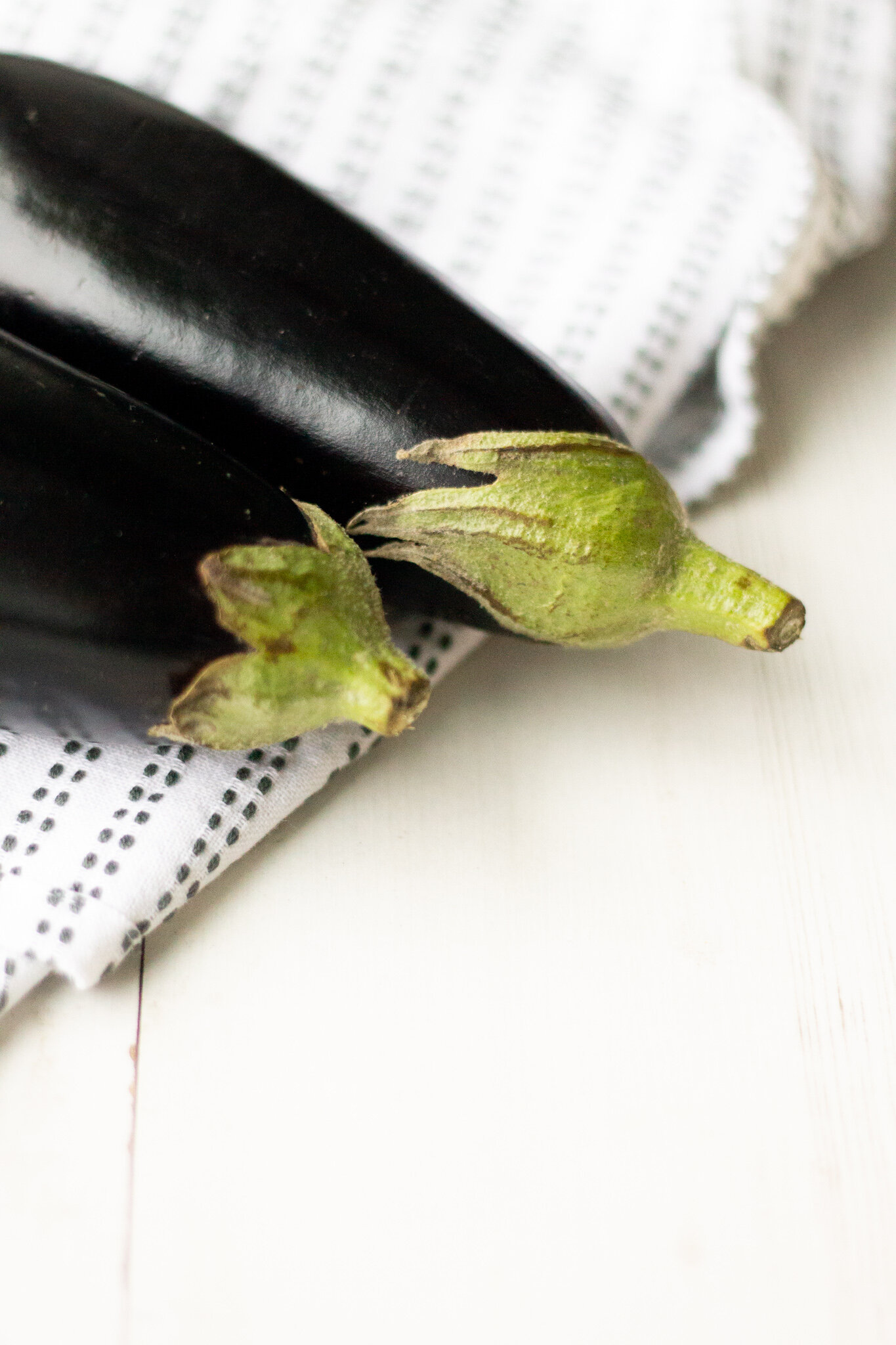 two aubergines on top of a kitchen towel