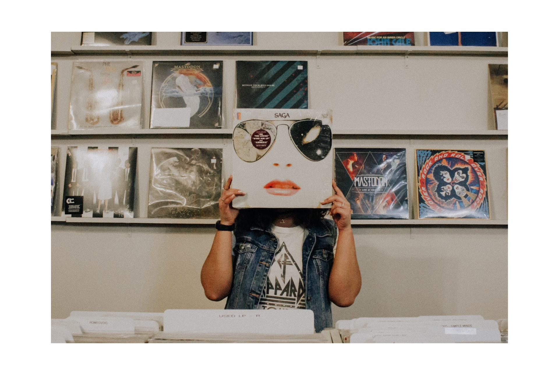 Person holding record cover over face in record store