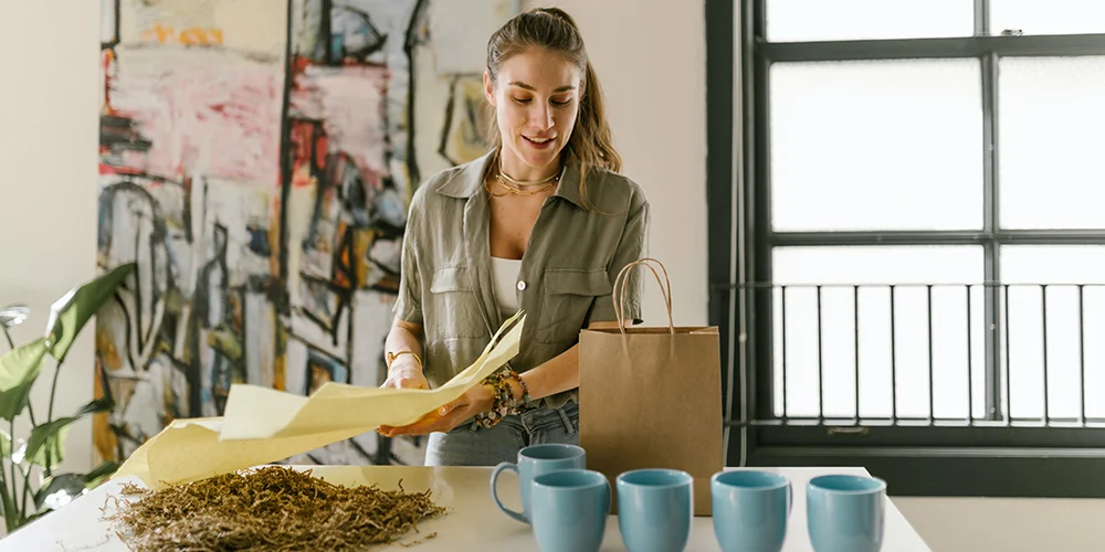 kupalar ve bitkilerle sipariş hazırlayan kadın