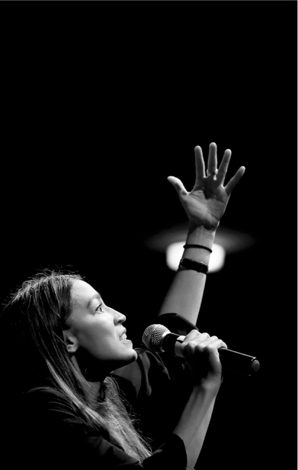 Woman singing with a hand up