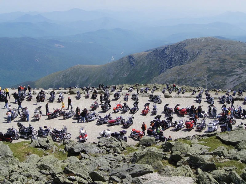 dozens of motorcycles parked at a scenic look out