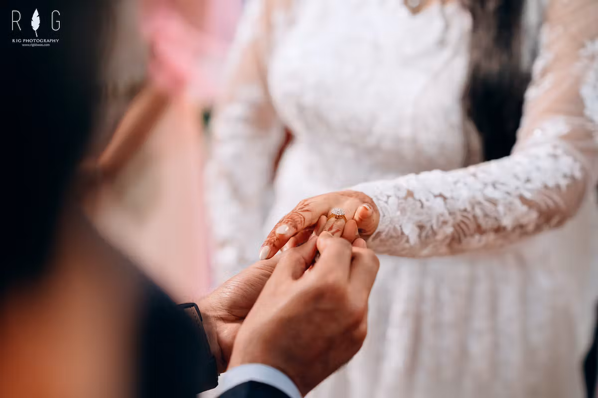 Photo of ring exchange ceremony where groom is exchanging ring with his bride
