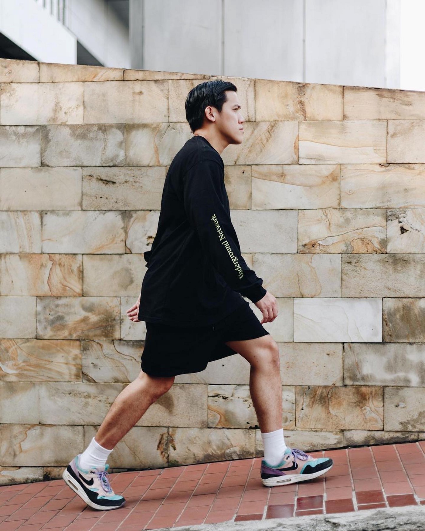 A man who wears sports fashion style clothing and shoes walk on the street.