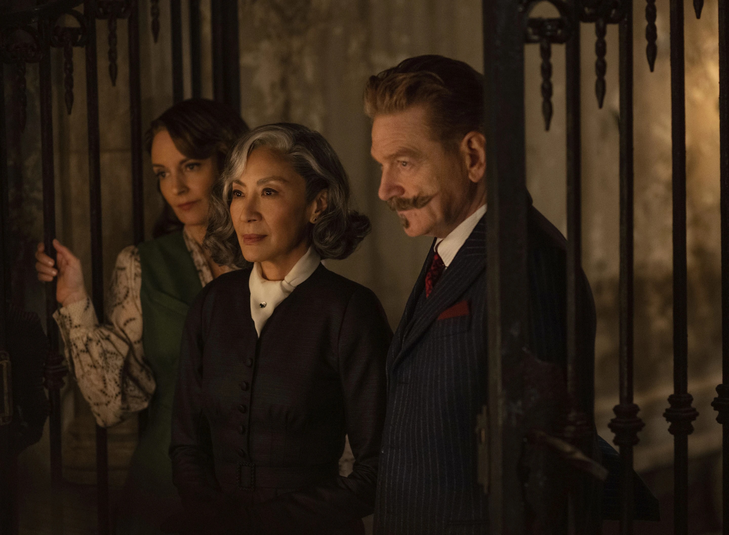 Two women and one man stand in a dark, haunting room