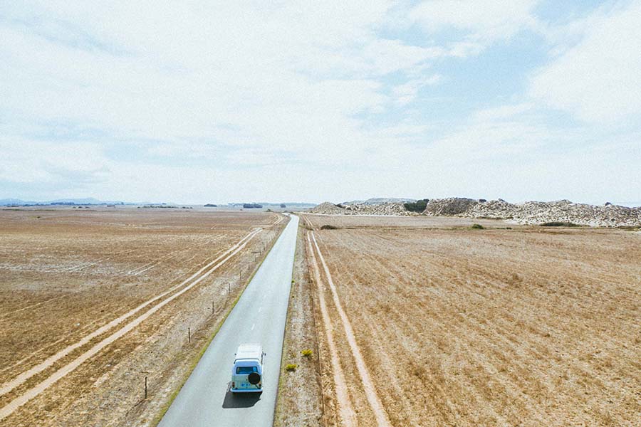 Volkswagen camper van driving down an empty road in Portugal.