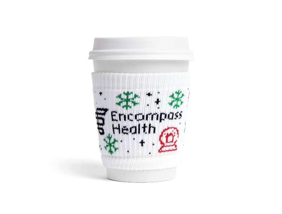 Custom woven beverage holder, called a slippy, branded for Encompass Health, on a white coffee cup
