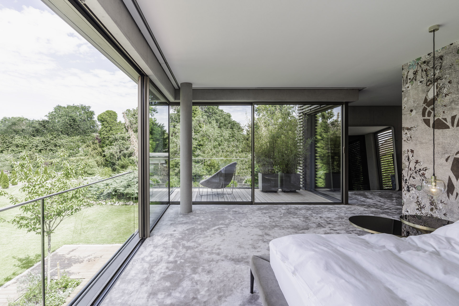 modern bedroom with glazing on all sides and trees outside