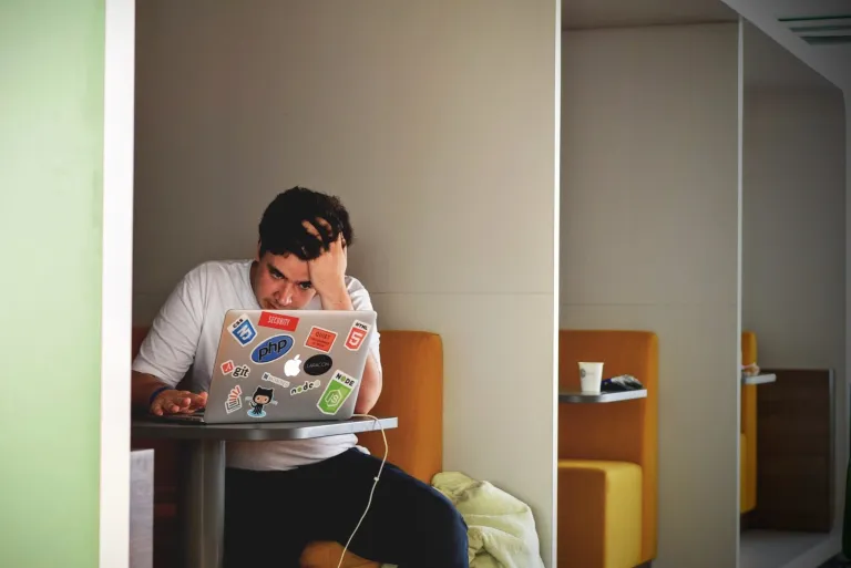 Man looking distressed working on a laptop