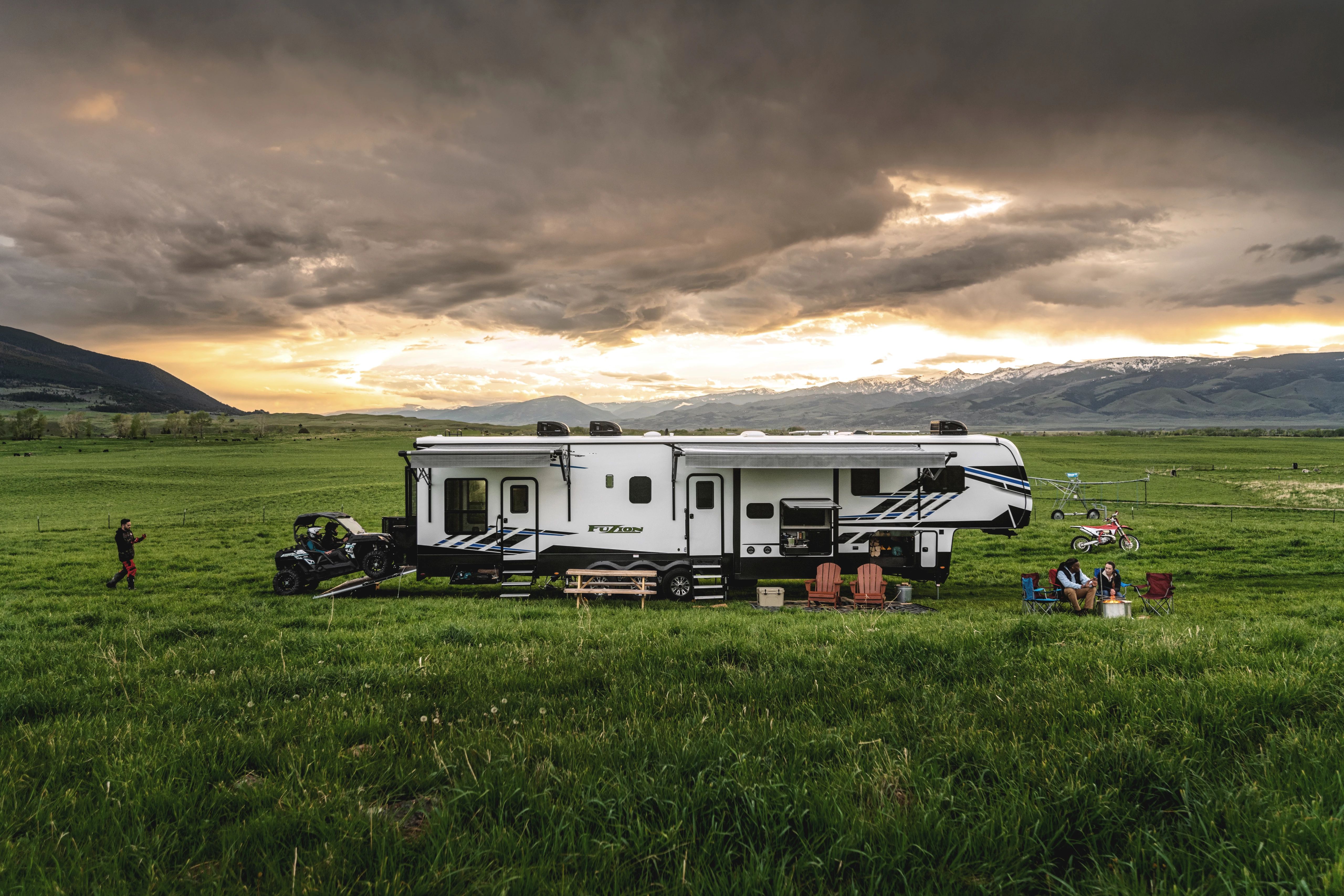 a group of friends with a fifth wheel RV boondocking in a field 