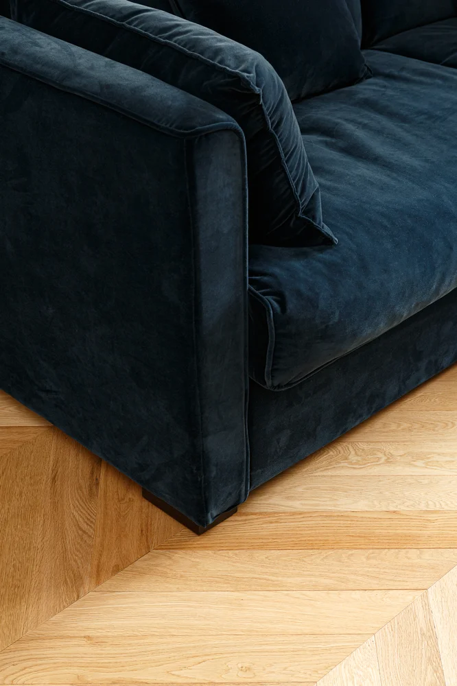 Canapé en velours bleu nuit et parquet stratifié